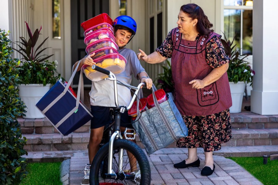 A grandmother sends her grandson off on his bike with food containers, from a Chalant campaign